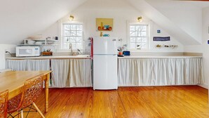 A kitchen with a wooden table, a refrigerator, and a microwave.
