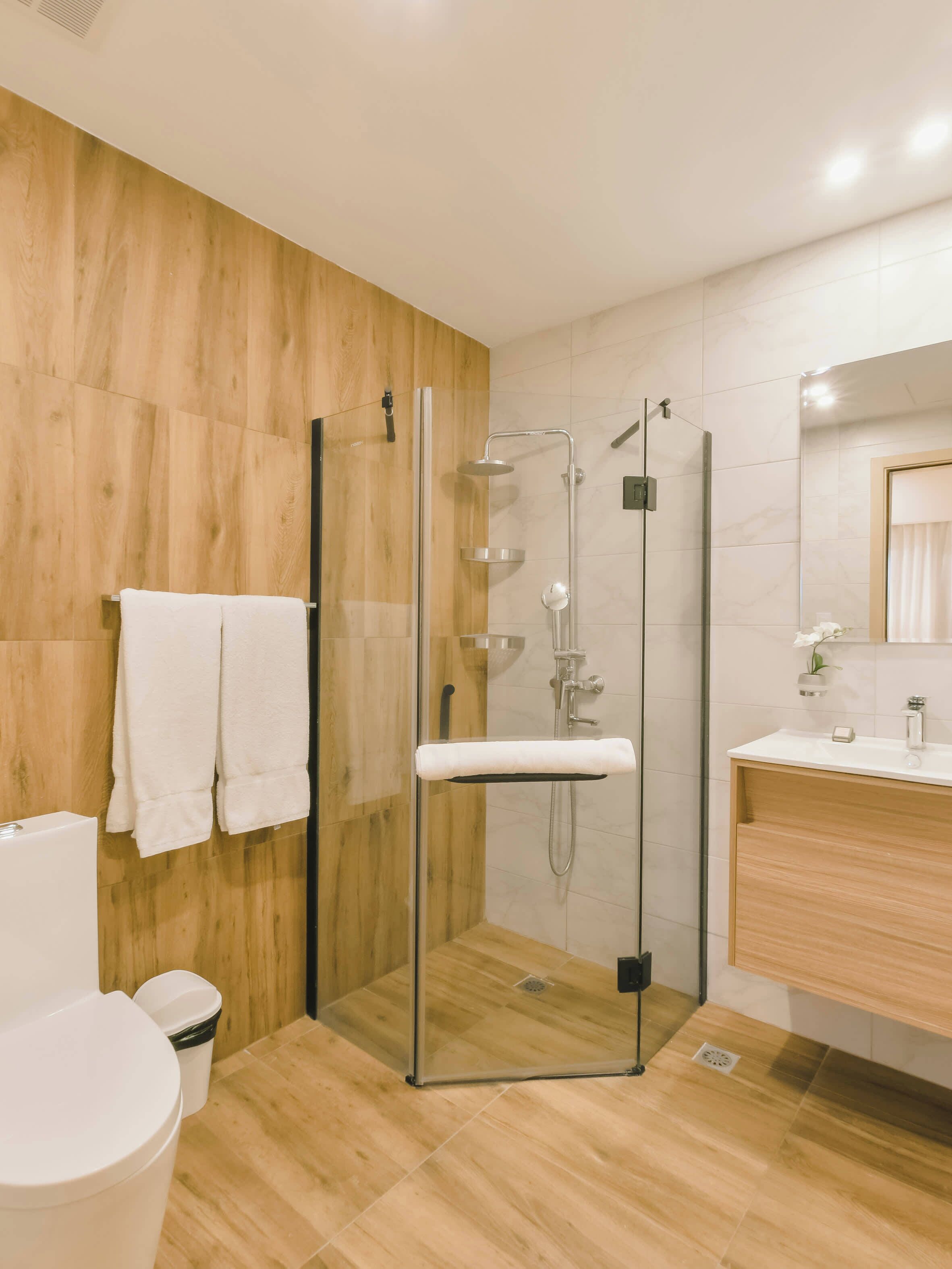 Un baño moderno con cabina de ducha de vidrio, inodoro y tocador con espejo.