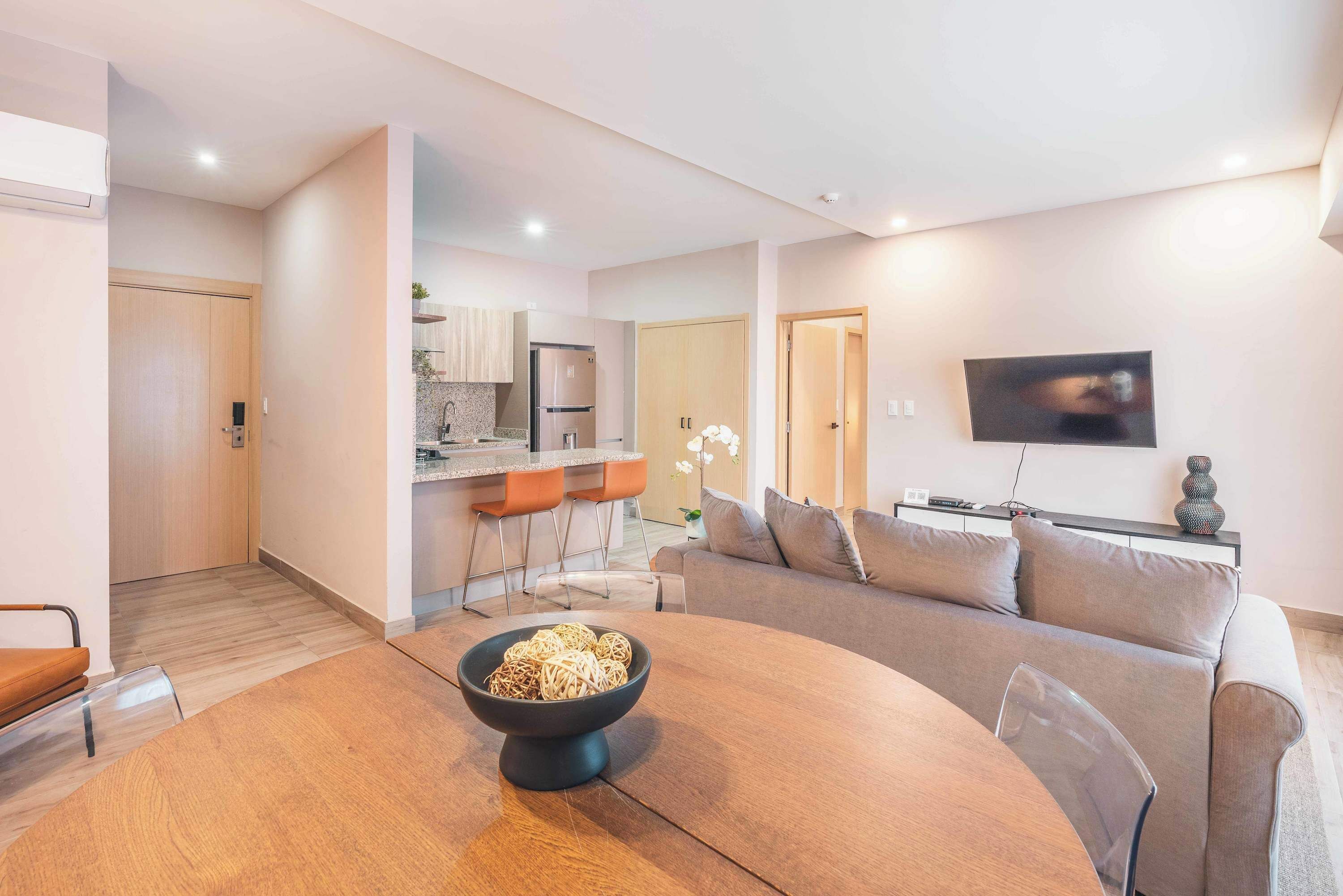 Een moderne woonkamer met een ronde eettafel, een bank en een keuken in de achtergrond.