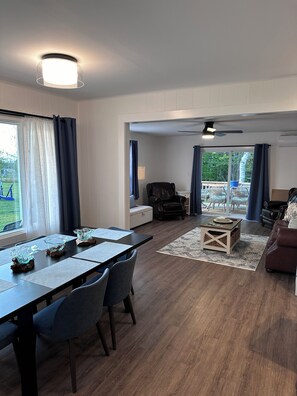 A spacious living area with a dining table, chairs, a sofa, and a ceiling fan. -  Stage View Cottage: 5 Minutes to Cavendish Beaches (New Glasgow)