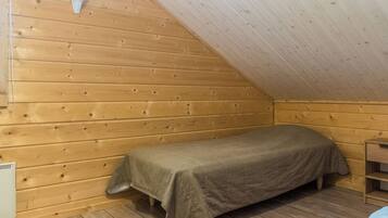 Une petite chambre avec un lit simple, des murs en bois et un plafond en pente.