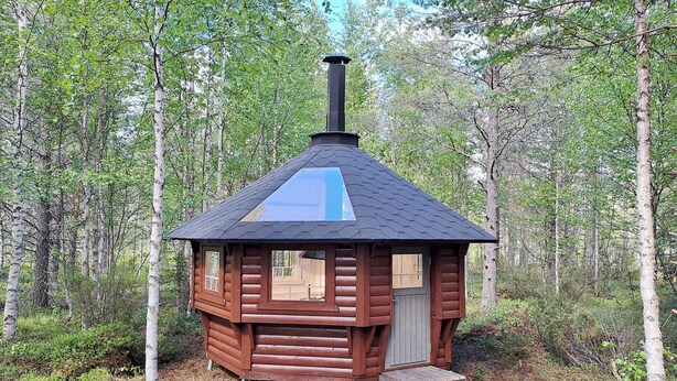 Eine kleine Holzhütte mit Schornstein, Tür und Fenster.