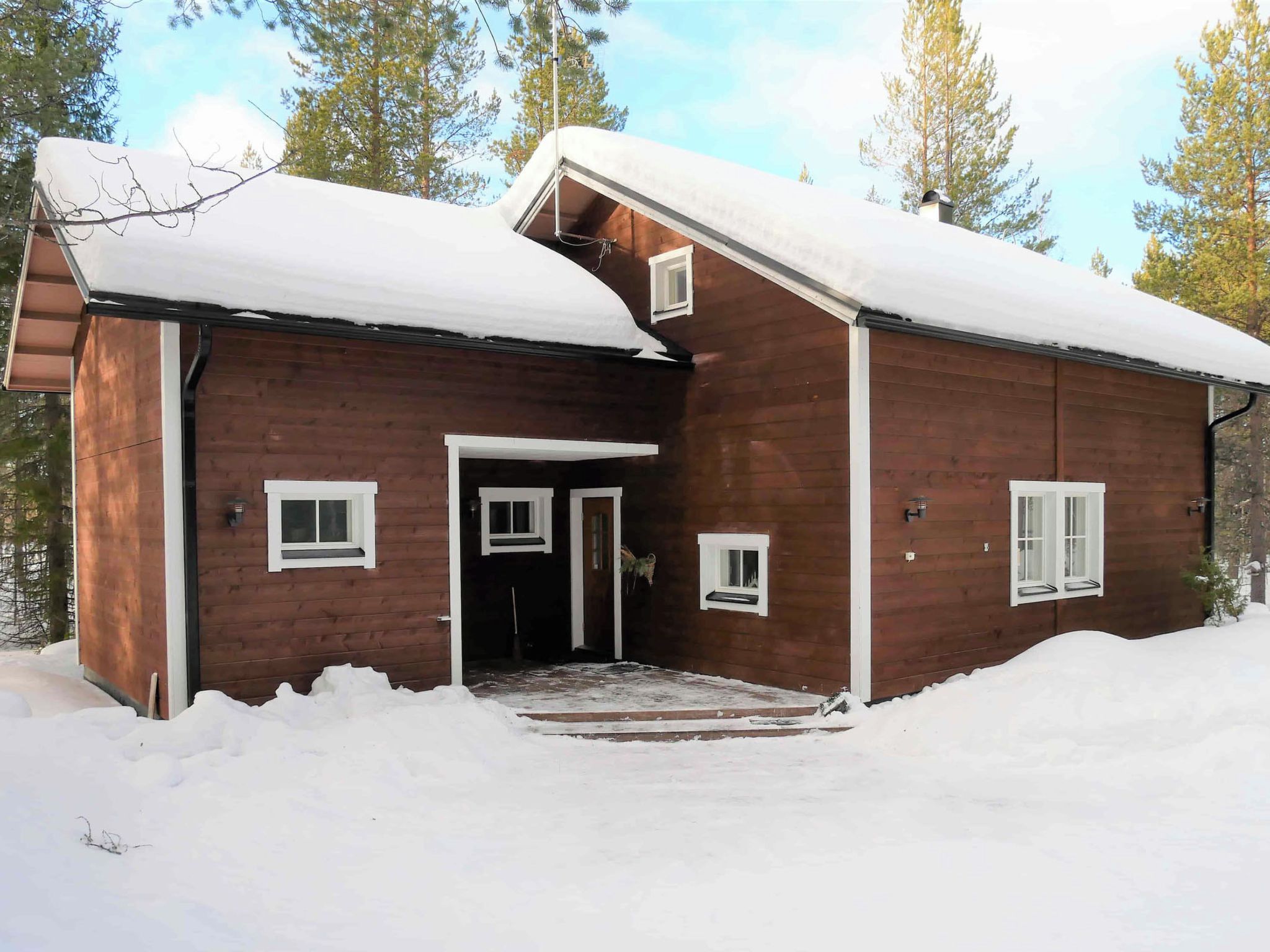 A wooden cabin with a snow-covered roof and a front door.