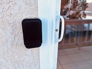 Una puerta con manija y un objeto negro sujeto a la pared.