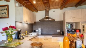 A modern kitchen with a central island, stainless steel appliances, and a rustic ceiling. - Les Fleurs de l'Aubrac 4/6 pers (SAINTE-COLOMBE-DE-PEYRE)