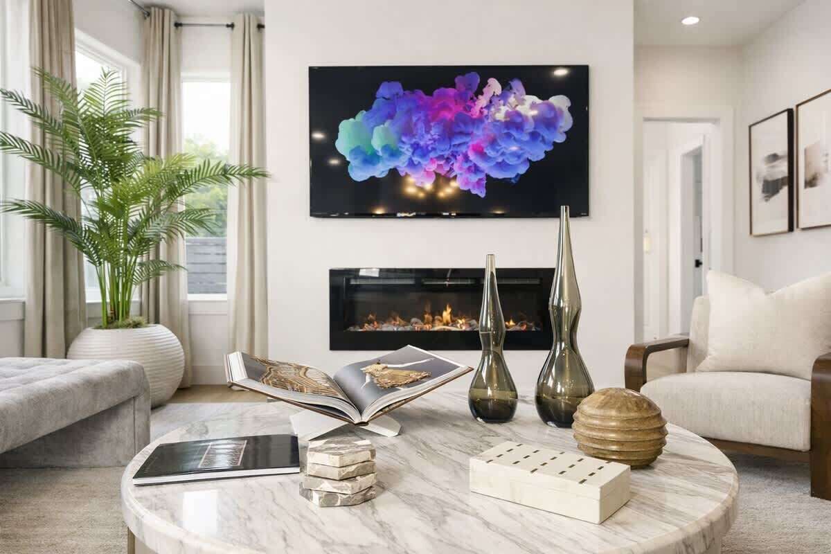 A living room with a fireplace, a television, a plant, and a coffee table.