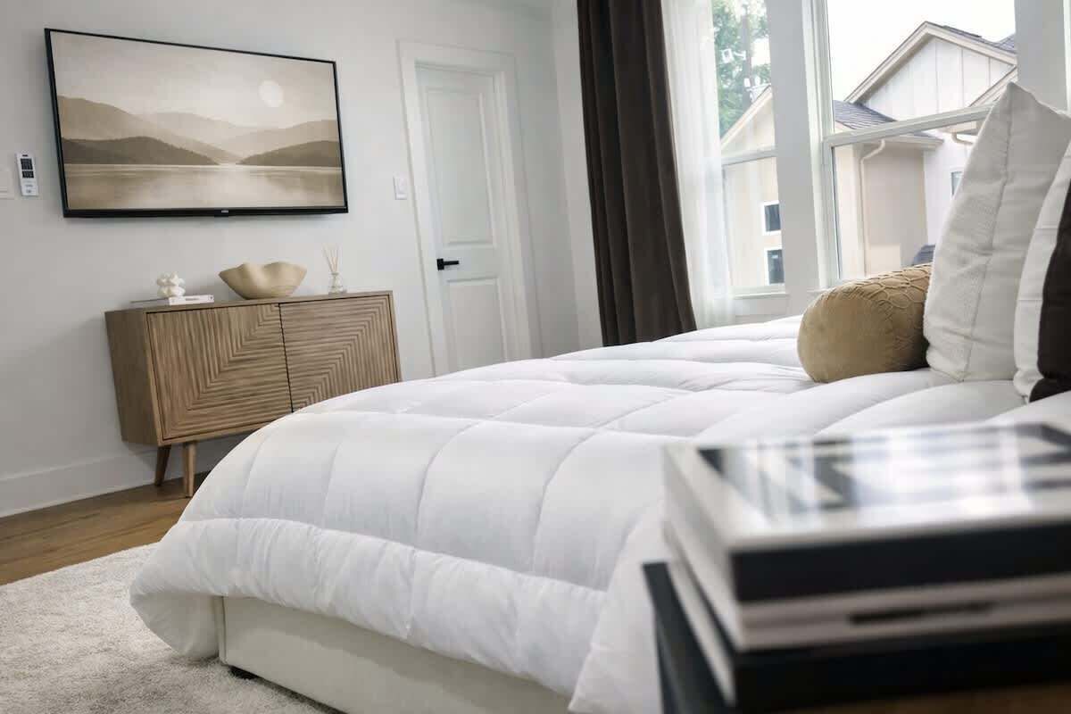 Un dormitorio con cama, cómoda, un cuadro y ventana.