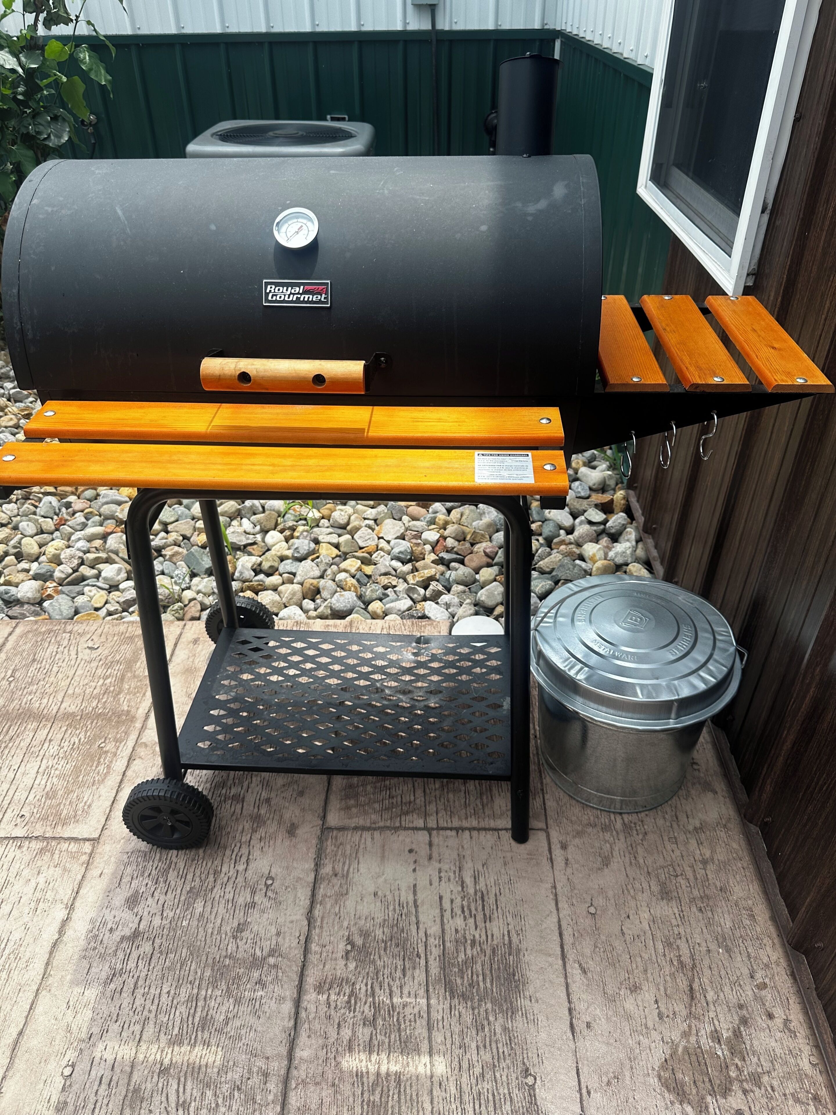 A portable grill with a metal container and a wooden bench.