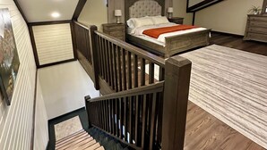A bedroom with a bed, a nightstand, a dresser, a staircase, and a ceiling with recessed lighting.