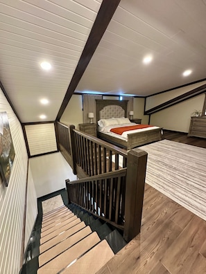 A bedroom with a bed, a nightstand, a dresser, a staircase, and a ceiling with recessed lighting. - Providence Rustic Retreat-Couples Getaway! (Woodburn)