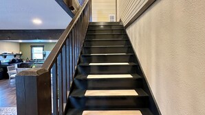 A staircase with black steps and wooden railings leading to an upper floor.