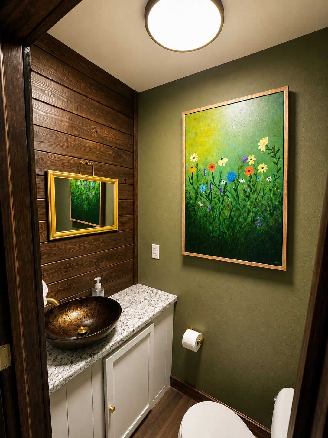 Une salle de bain avec un meuble-lavabo en bois, un lavabo sur colonne, des toilettes, un tableau encadré et un miroir.