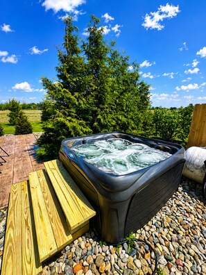 A hot tub with a wooden bench, surrounded by pebbles and greenery. - Providence Rustic Retreat-Couples Getaway! (Woodburn)
