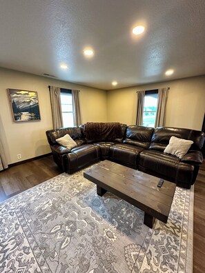 A living room with a sectional sofa, a coffee table, patterned rug, and a painting on the wall.