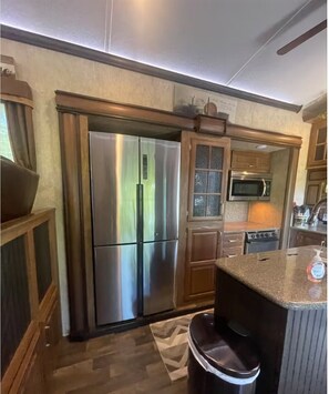 Eine Küche mit Edelstahlkühlschrank, Holzschränken, einer Mikrowelle und einer Arbeitsplatte aus Granit.