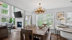 Ein modernes Wohnzimmer mit Kamin, Esstisch und Barbereich.