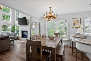Ein modernes Wohnzimmer mit Kamin, Esstisch und Barbereich.