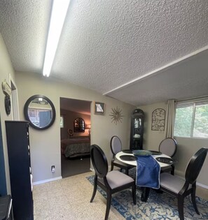 A dining area with a round table, chairs, a clock, and a mirror on the wall. - Quaint Cabin at The Lake! (Camdenton)