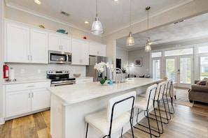 A modern kitchen with white cabinets, stainless steel appliances, and a central island with bar stools.