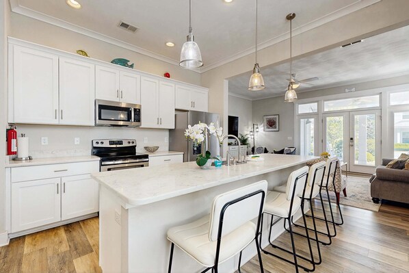 A modern kitchen with white cabinets, stainless steel appliances, and a central island with bar stools.