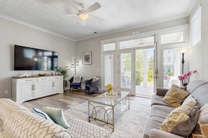 A living room with a TV, sofa, coffee table, and a dining area with a cabinet.