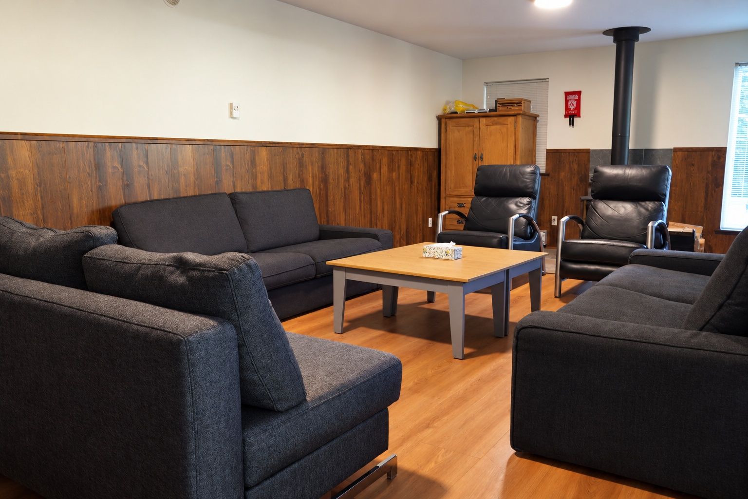 A room with a sofa, a chair, a table, and a cabinet.