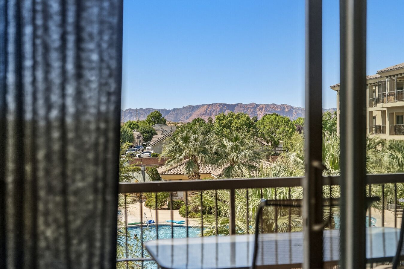 Ein Balkon mit Pool, Palmen und Bergen im Hintergrund.