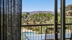 Ein Balkon mit Pool, Palmen und Bergen im Hintergrund.