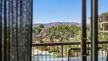 Ein Balkon mit Pool, Palmen und Bergen im Hintergrund.