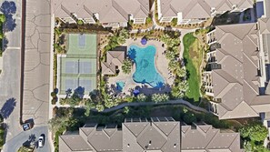 Vue aérienne d’un quartier résidentiel avec une piscine, des courts de tennis et un parking.