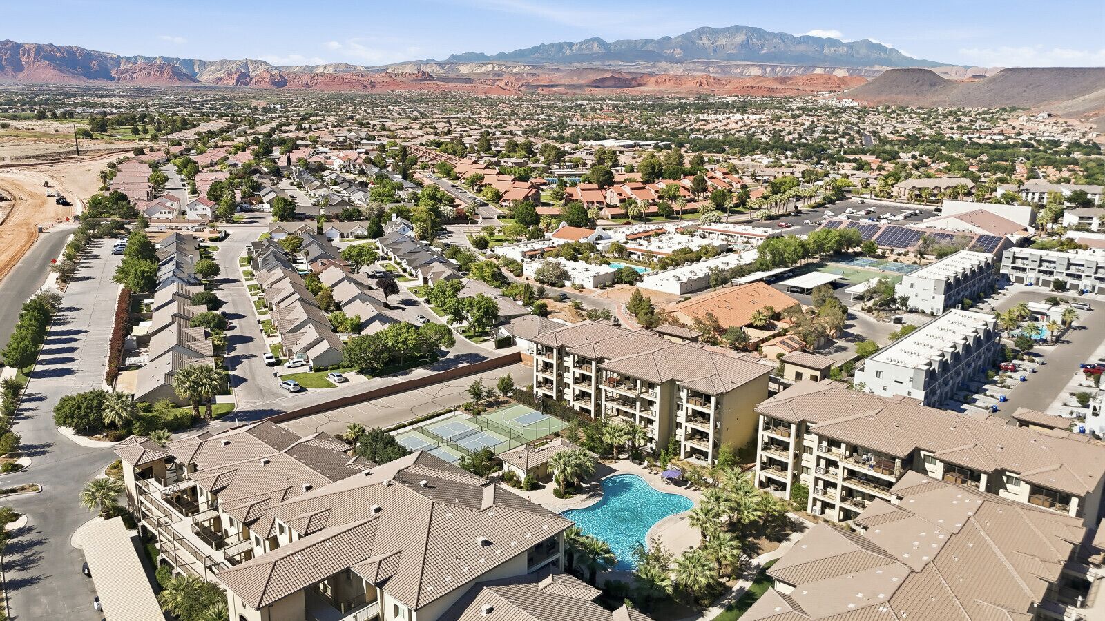 A resort with multiple buildings, a swimming pool, and a mountainous backdrop.