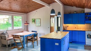A kitchen with blue cabinets, a wooden island, and a dining area with a table and chairs.