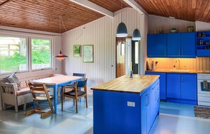 Eine Küche mit blauen Schränken, einer Holzinsel und einem Essbereich mit Tisch und Stühlen.