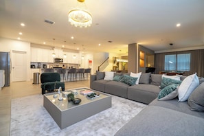 Ein modernes Wohnzimmer mit einem grauen Sofa, einem Couchtisch und einer Deckenleuchte.