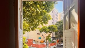 An open door leading to a balcony with a view of a city street, buildings, and trees. - Cocos Hostel Rio (Rio de Janeiro)