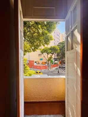 A view from a window with a door frame, a building with a yellow wall, and a tree in the background. - Cocos Hostel Rio (Rio de Janeiro)