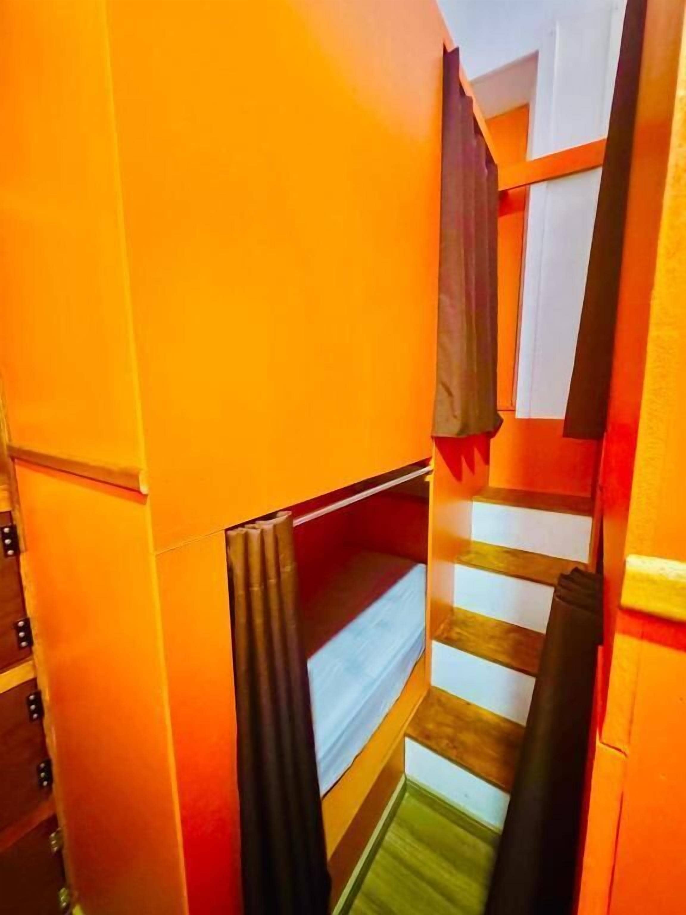A narrow hallway with a bunk bed, wooden steps, and a curtain.