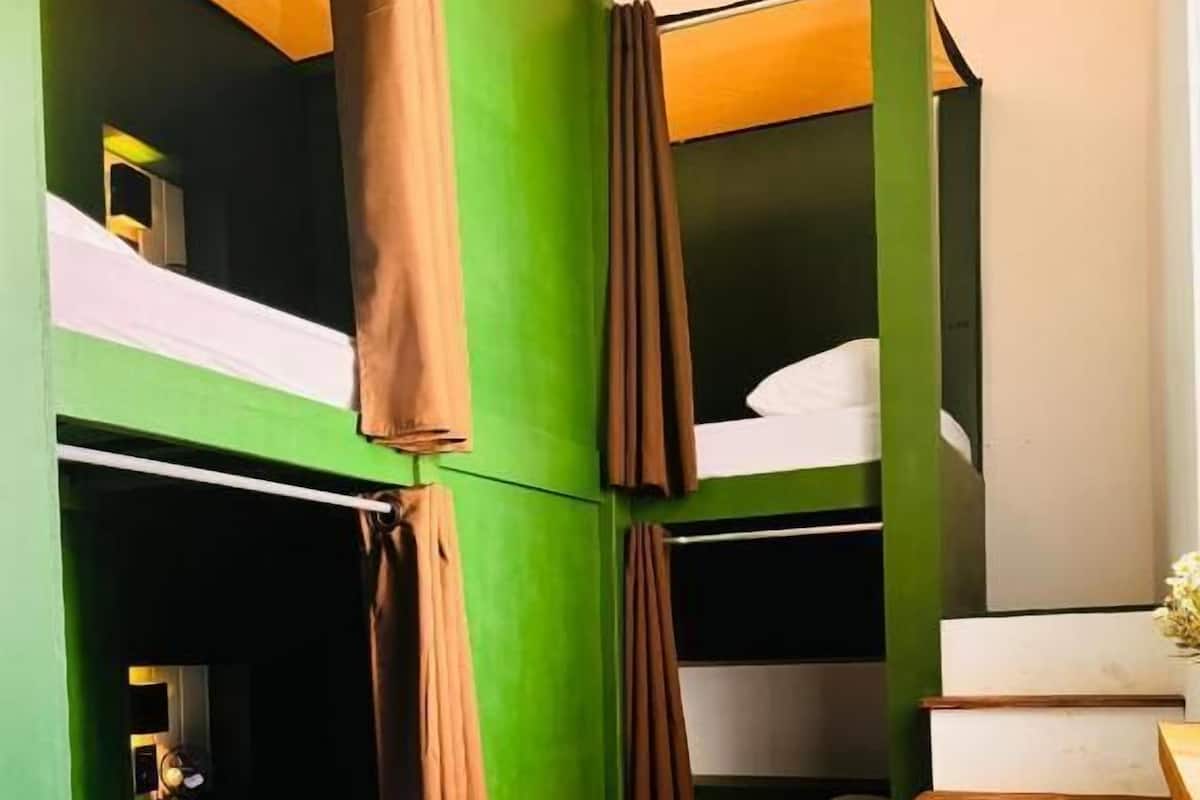 A room with bunk beds, a small table, and a staircase.