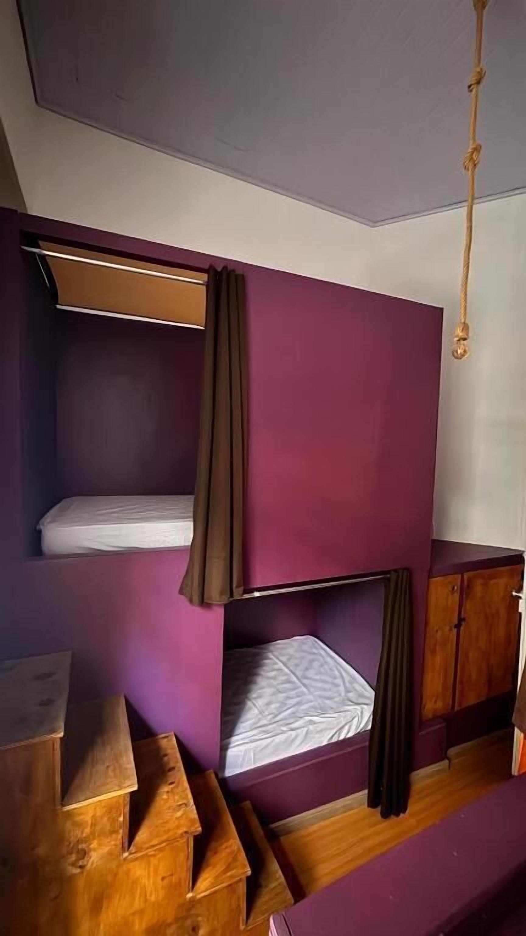 A bunk bed room with a wooden desk, a cabinet, and a hanging light fixture.