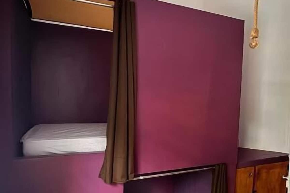 A bunk bed room with a wooden desk and a cabinet.