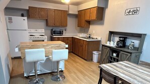 A compact kitchen with wooden cabinets, a white refrigerator, a microwave, a stove, and a coffee station. - Cozy 2-bedroom in quaint Sturgis.  1 Mile to Main Street (Sturgis)