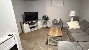 A living room with a fireplace, a television, a couch, a coffee table, and a ceiling fan. - Cozy 2-bedroom in quaint Sturgis.  1 Mile to Main Street (Sturgis)