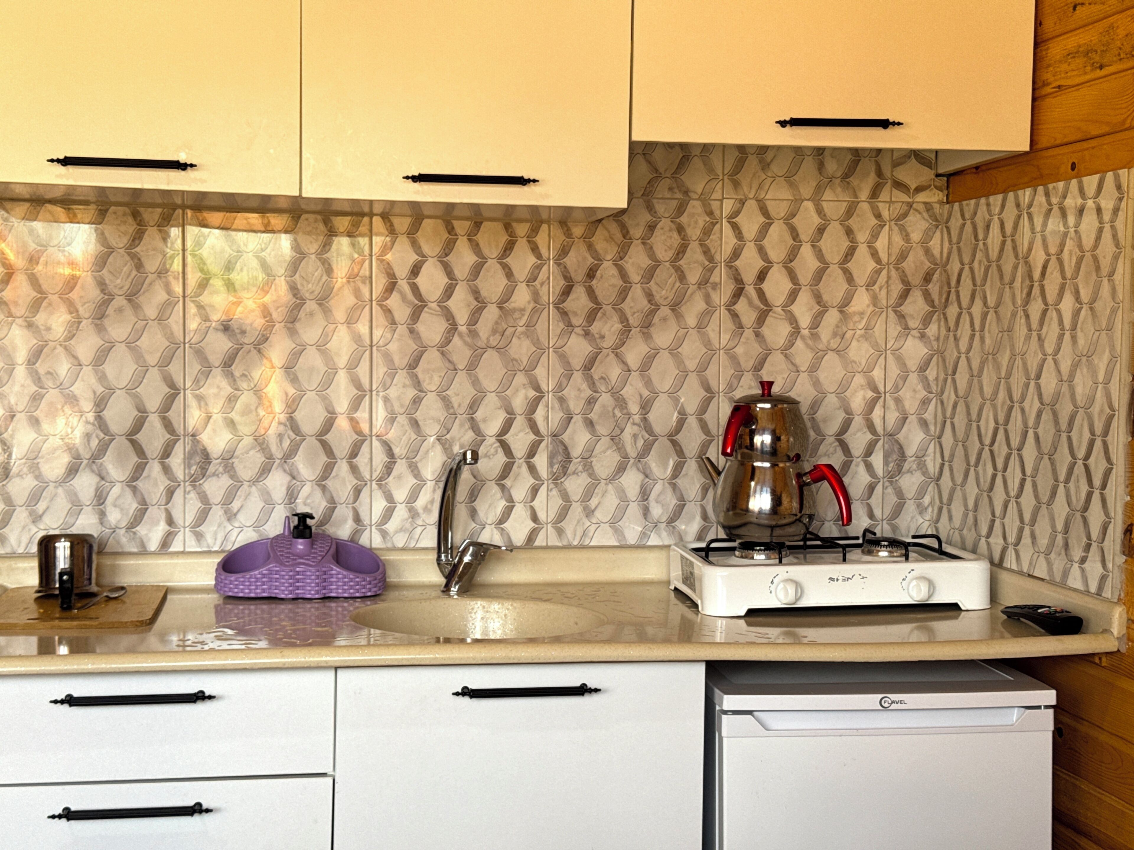 A kitchen with a patterned backsplash, a gas stove, a sink, and a dishwasher.