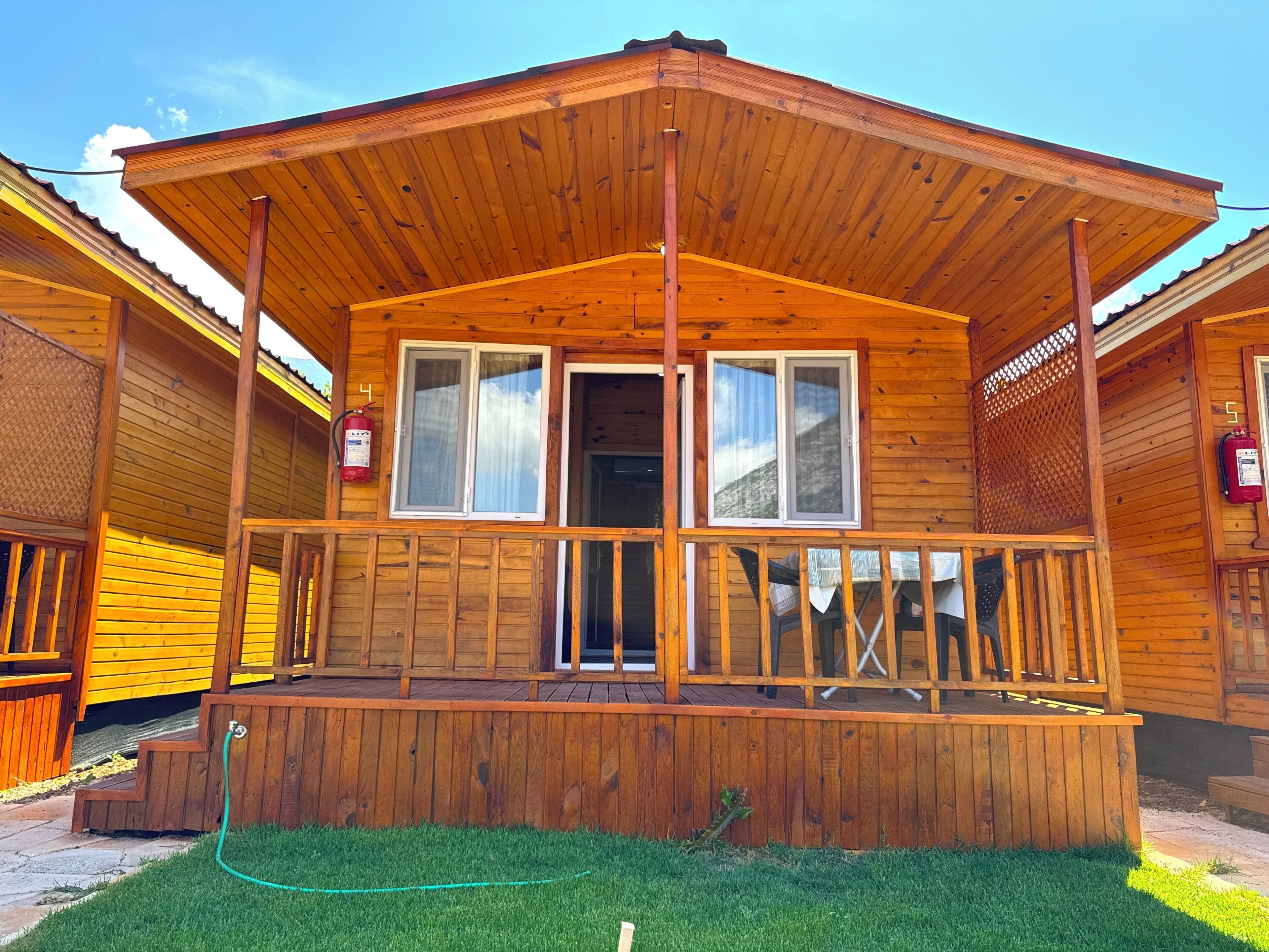 A wooden cabin with a porch, a fire extinguisher, and a hose.