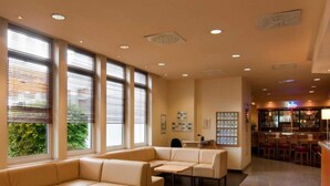 Hall d'albergo con angolo relax, reception e bar.