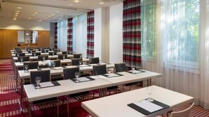 Una sala conferenze con tavoli, sedie e uno schermo per proiezioni.