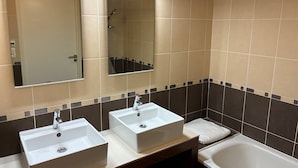 Ein Badezimmer mit zwei Waschbecken, einem Spiegel, einer Dusche und einer Badewanne.