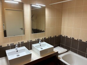 Ein Badezimmer mit zwei Waschbecken, einem Spiegel, einer Dusche und einer Badewanne.