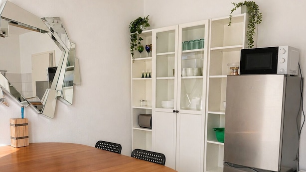 Eine moderne Küche mit einem runden Holztisch, schwarzen Stühlen, einem Edelstahlkühlschrank und einer Spiegelwand.