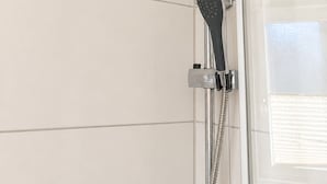 Eine Dusche mit Duschkopf und Handbrause.